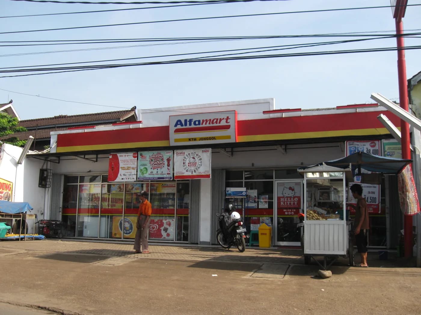Gerai Alfamart dengan papan nama merah kuning di tepi jalan